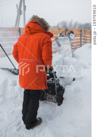 A man clear snow from backyard with snow blower. Winter season and snow blower equipment A man clear snow from backyard with snow blower. Winter season and snow blower equipment 109769610