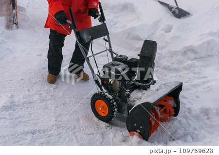 A man clear snow from backyard with snow blower close-up. Winter season and snow blower equipment close-up 109769628