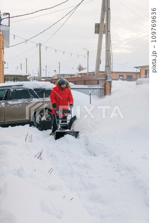A man clear snow from backyard with snow blower. Winter season and snow blower equipment A man clear snow from backyard with snow blower. Winter season and snow blower equipment 109769636