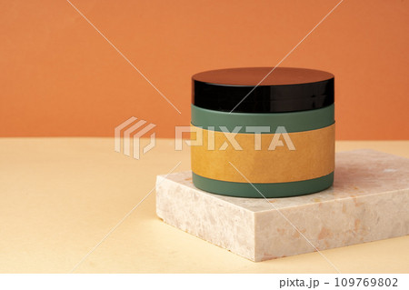 Cosmetic jar and stone on brown background Cosmetic jar and stone on brown background 109769802