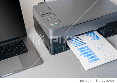 Printer and laptop on grey table in office Printer and laptop on grey table in office 109770254