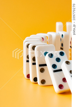 Row of domino tiles on yellow studio background 109770270