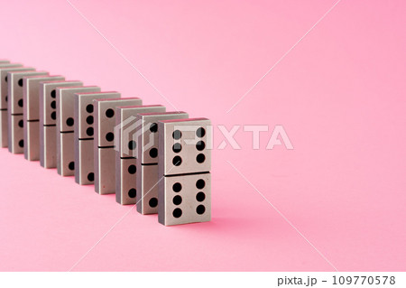 Row of domino tiles on pink studio background 109770578