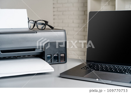 Printer and laptop on grey table in office Printer and laptop on grey table in office 109770753