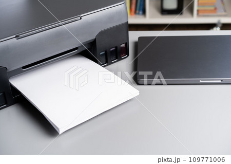 Printer and laptop on grey table in office Printer and laptop on grey table in office 109771006