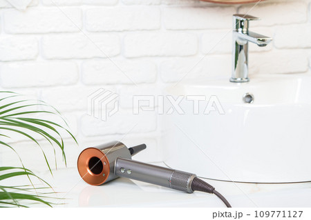 Electric hair dryer on counter in the bathroom. Electric hair dryer on counter in the bathroom. 109771127