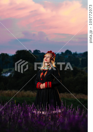 The girl is wearing a chelsea headdress and a black dress decorated with red embroidery The girl is wearing a chelsea headdress and a black dress decorated with red embroidery 109772073