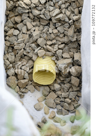 Yellow corrugated pipe with perforation in a trench with crushed stone and geotextile. Drainage works for the removal of ground water. Yellow corrugated pipe with perforation in a trench with crushed stone and geotextile. Drainage works for the removal of ground water. 109772132