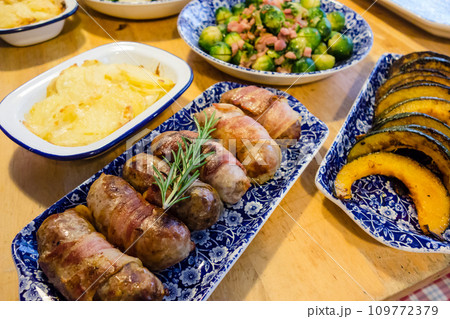 青色のお皿に盛られたクリスマスディナー料理 ソーセージと芽キャベツとポテトパイ 青色のお皿に盛られたクリスマスディナー料理 ソーセージと芽キャベツとポテトパイ 109772379