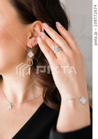 Detail of young woman wearing beautiful luxury earring and bracelet. Handmade jewellery and accessories Detail of young woman wearing beautiful luxury earring and bracelet. Handmade jewellery and accessories 109772674
