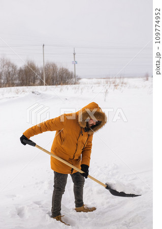 Young man clearing snow in his backyard village house with shovel. Remove snow from the sidewalk. Young man clearing snow in his backyard village house with shovel. Remove snow from the sidewalk. 109774952