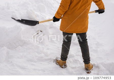 Close-up man is clearing the snow near house and on staircases hovelling at the winter season. Winter storm and season specific 109774953