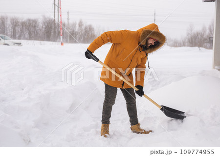 Man cleaning snow from sidewalk and using snow shovel. Winter season Man cleaning snow from sidewalk and using snow shovel. Winter season 109774955