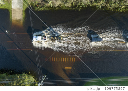 Flooded road in Florida after heavy hurricane rainfall. Aerial view of evacuating cars and surrounded with water houses in suburban residential area Flooded road in Florida after heavy hurricane rainfall. Aerial view of evacuating cars and surrounded with water houses in suburban residential area 109775897