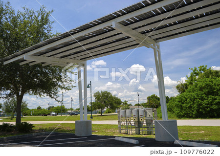 Solar panels installed as shade roof over parking lot for parked electric cars for effective generation of clean electricity. Photovoltaic technology integrated in urban infrastructure 109776022