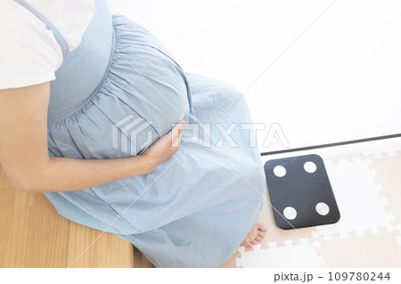 体重計の前に座る妊婦女性 体重計の前に座る妊婦女性 109780244
