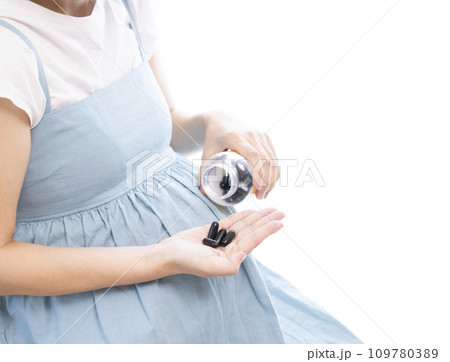 妊婦の女性がサプリメントを摂取するイメージ 109780389