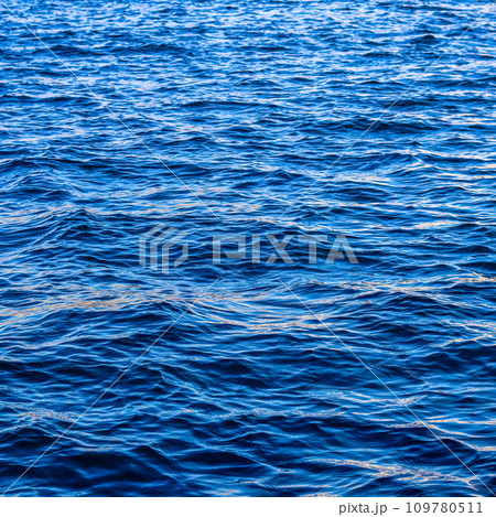 Blue sea waves in sunshine glow as surface background. Summer holidays and coastal nature concept 109780511