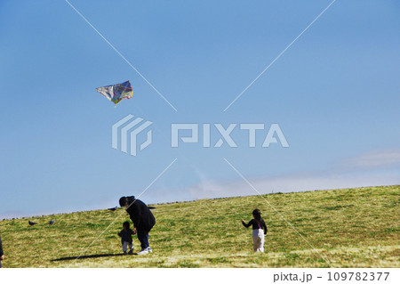 正月の遊び。家族で公園で凧上げをする。風に乗って凧は舞い上がり、子供の興奮した喜びの声が聞こえる 正月の遊び。家族で公園で凧上げをする。風に乗って凧は舞い上がり、子供の興奮した喜びの声が聞こえる 109782377