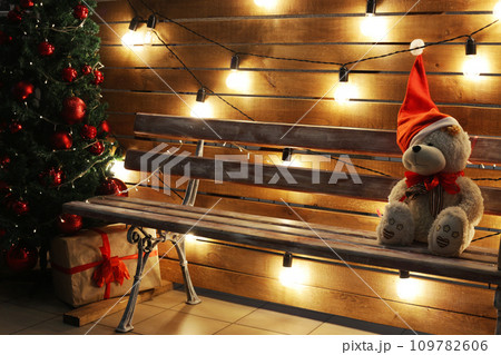 Teddy bear alone on a bench near the Christmas tree. Teddy bear alone on a bench near the Christmas tree. 109782606