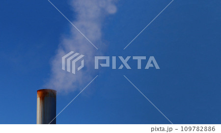 A metal, rusty pipe with smoke rising up 109782886