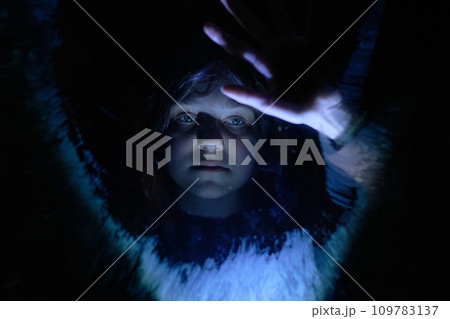 A lonely girl behind glass in a dark room is waiting for help 109783137