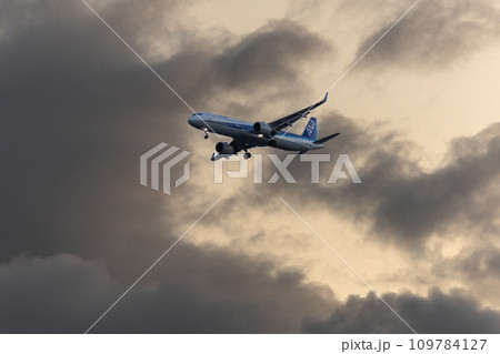 夕暮れの空をゆく飛行機 109784127