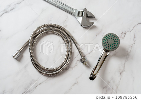 Handheld showerhead, hose and wrench ready for changing. 109785556