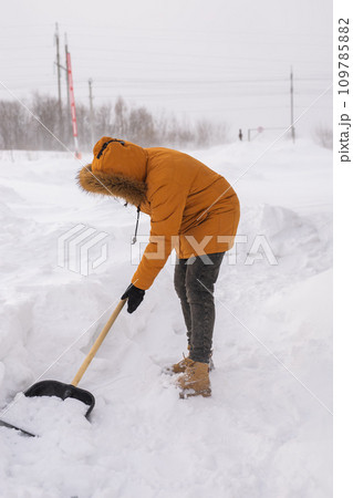 Man is clearing the snow near house and on staircases hovelling at the winter season. Winter storm and season specific 109785882