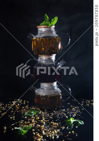 Glass teapots with tea. Teapots stand on top of each other. Healthy drink. Hot tea. Mint leaves. Glass teapots with tea. Teapots stand on top of each other. Healthy drink. Hot tea. Mint leaves. 109787838