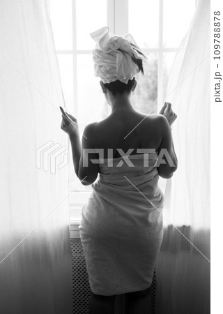 Portrait on back view of bare shoulder woman looking at the window in black and white 109788878