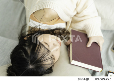 本を抱えて寝転ぶ若い女性 109789357