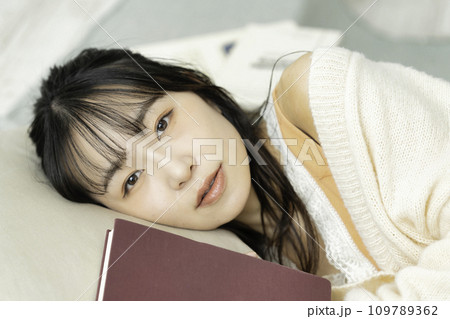 本を抱えて寝転ぶ若い女性 109789362