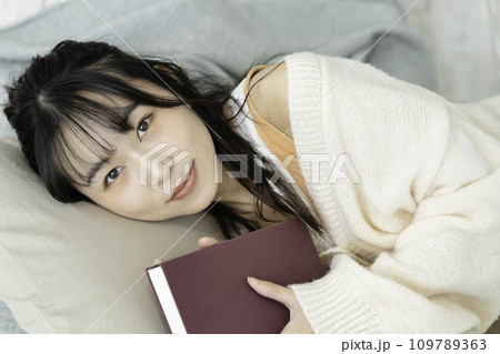 本を抱えて寝転ぶ若い女性 109789363