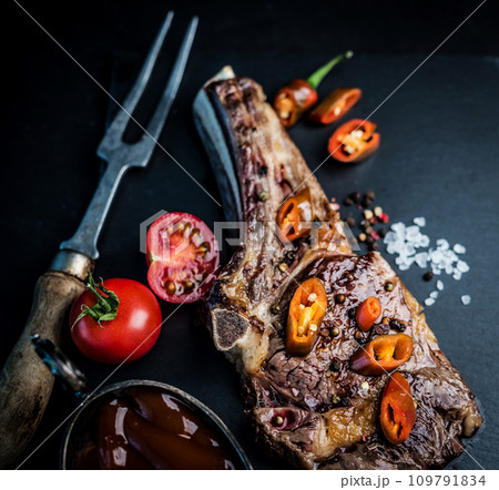 Beef grilled steak served with tomatoes, chili pepper and sauce Beef grilled steak served with tomatoes, chili pepper and sauce 109791834