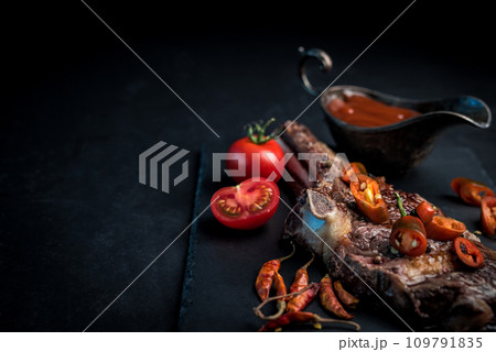 Grilled hot ribeye beef steak on bone with spicy sauce Grilled hot ribeye beef steak on bone with spicy sauce 109791835