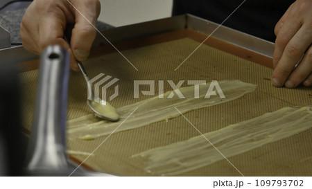 Preparation of homemade cakes. A man smears cake with cream Preparation of homemade cakes. A man smears cake with cream 109793702