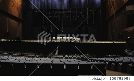 Meeting room before the educational conference. Media. Man going up the stairs among empty rows of chairs in front of the stage with beige armchairs. Meeting room before the educational conference. Media. Man going up the stairs among empty rows of chairs in front of the stage with beige armchairs. 109793995