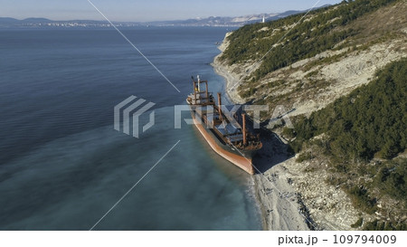 Aerial view of large cargo ship in still blue water near coastline. Shot. Sea transportations Aerial view of large cargo ship in still blue water near coastline. Shot. Sea transportations 109794009