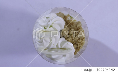 Sweet dessert in glass with biscuit, whipped cream. Ice cream with whipped cream close up 109794142