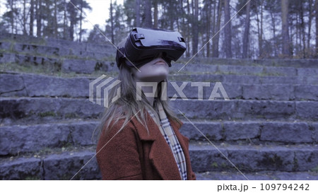 Fair-haired girl outdoor Have fun in VR glasses. Teenager girl enjoying virtual reality glasses outdoor in the park. Pretty girl enjoy virtual reality glasses outdoor 109794242
