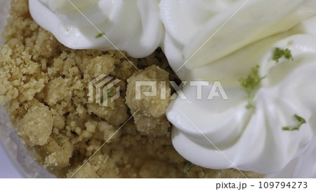 Sweet dessert in glass with biscuit, whipped cream. Ice cream with whipped cream macro Sweet dessert in glass with biscuit, whipped cream. Ice cream with whipped cream macro 109794273
