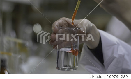 Chemist hands mixed substance of red color in test tubes. Doctor Pours red Chemicals Into In Flask. Close Up 109794289