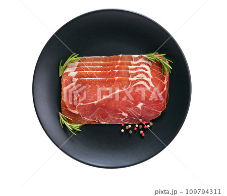 Slices of parma ham prosciutto with rosemary and spice in a plate isolated on white background. 109794311