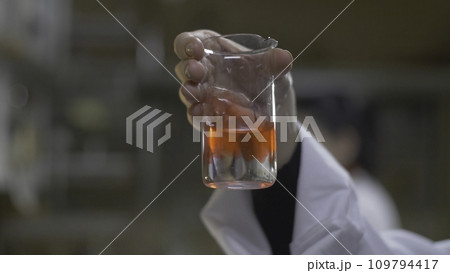 Chemist hands mixed substance of red color in test tubes. Doctor Pours red Chemicals Into In Flask. Close Up 109794417