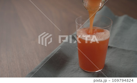 pour red orange drink into tumbler glass with copy space 109794824