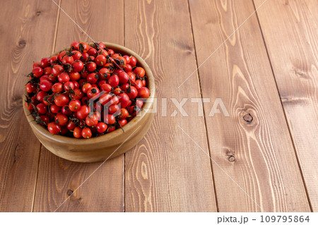 red dog-rose rosehip fruits in a wooden bowl on wooden table red dog-rose rosehip fruits in a wooden bowl on wooden table 109795864