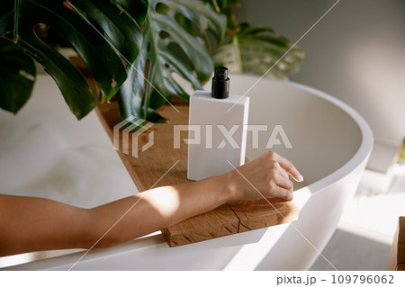 Bottle of hygiene product for bathing on bathtub and female hand 109796062