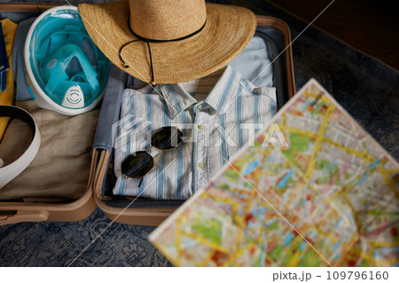 Opened travel suitcase with clothes and paper map selective focus Opened travel suitcase with clothes and paper map selective focus 109796160