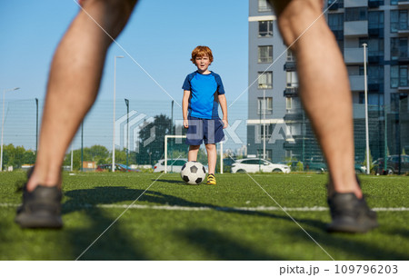 Father and son playing family football summer camp at city stadium Father and son playing family football summer camp at city stadium 109796203